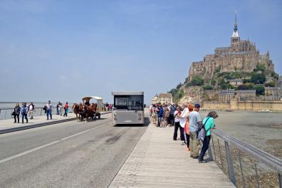 Auf der neuen Brücke vor dem Mont Saint Michel begegnen sich der Bus-Shuttle (navette) und die Pferde-Kutsche